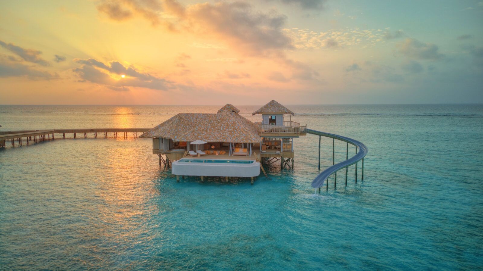 exterior view of an overwater villa with slide during sunset in soneva secret resort located in indian ocean.