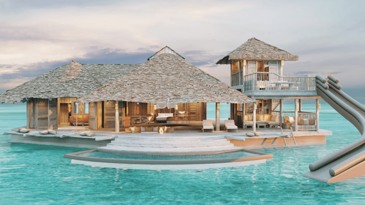 This picture shows an over water villa in india ocean with water slide and a pool with direct access to ocean.