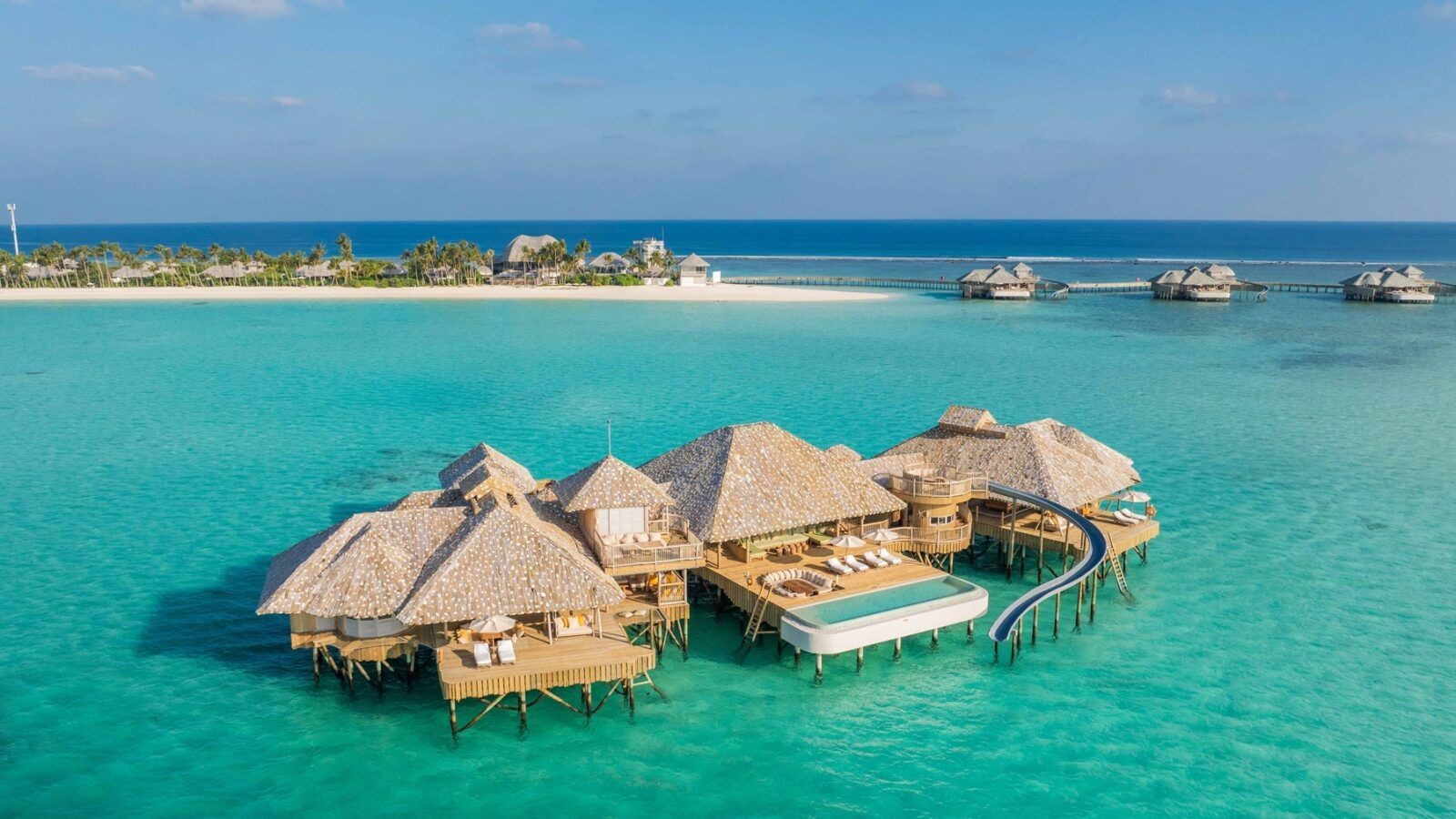 This image shows the exterior view of Crusoe Reserve overwater villa at Soneva secret resort Maldives with Water slide, pool and sunbeds.
